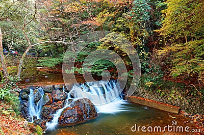 Beautiful scenery of a lovely waterfall tumbling down a rocky stream with colorful autumn foliage Stock Photo