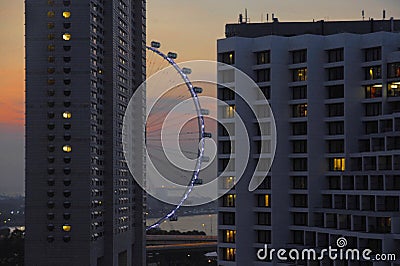 A beautiful scenic view of Singapore flyer attraction behind building blocks under a sunset orange sky evening Editorial Stock Photo