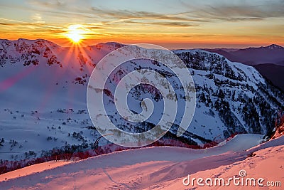 Beautiful scenic winter mountain sunset landscape of snowy Caucasus Mountains and ski slope of Gorki Gorod mountain ski resort in Stock Photo