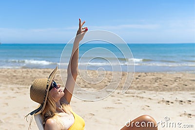 Beautiful seascape with a girl, a slender girl in a hat and swimsuit relaxes and lies on a sun lounger on the beach Stock Photo