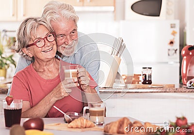 Beautiful senior couple having breakfast at home. Retired happy people drinking cappuccino eating fruit and croissant Stock Photo