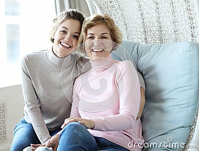 Beautiful senior mom and her adult daughter are hugging, looking at camera and smiling. Stock Photo