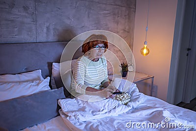 Senior woman watching horror movie Stock Photo