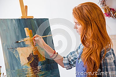 Beautiful serene young female painter painting picture in art workshop Stock Photo