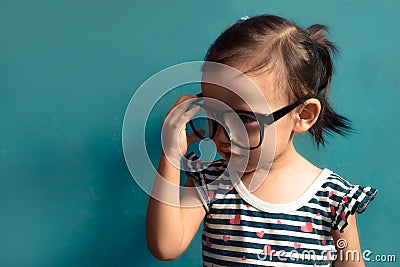 Beautiful serious children kid, girl holding glasses, blue isolated background with copy space Stock Photo