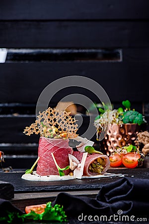 Beautiful serving of slice salted tuna with vegetables in a creamy sauce on a dark plate on a rustic wooden tray Stock Photo
