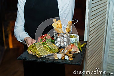 Beautiful set of food in the hands of a young waiter in a restaurant. close-up side view Stock Photo