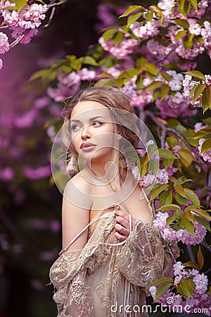 Beautiful adult girl standing at blossoming tree in the garden Stock Photo