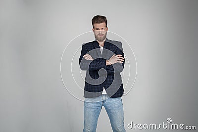 Beautiful sexy bearded man with a beautiful hair style. he is standing serious with crossed hands and looks at the camera. dressed Stock Photo