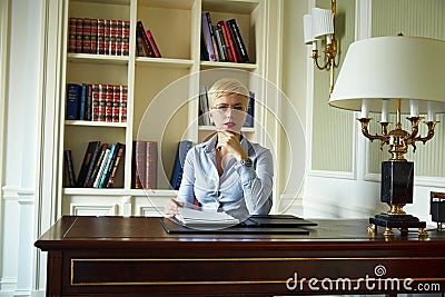 Beautiful sexy blonde woman in library parlor office read book meetings wear skinny skirt and blouse interior room classic style Stock Photo