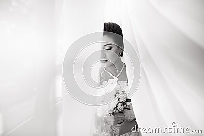 Beautiful sexy bride in white dress posing under curtain Stock Photo