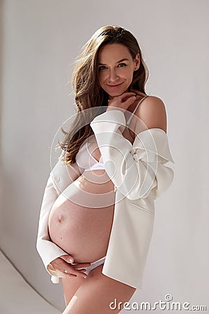 Beautiful sexy brunette woman pregnant belly lady on nine`s month happy Mather white skin wear white underwear and jacket on ligh Stock Photo