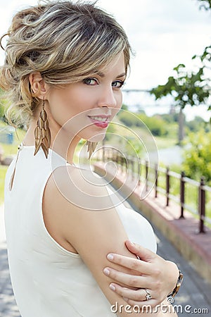 Beautiful cute girl with big lips and red lipstick with bared shoulders with a bouquet of daisies at sunset on a sunny warm Stock Photo