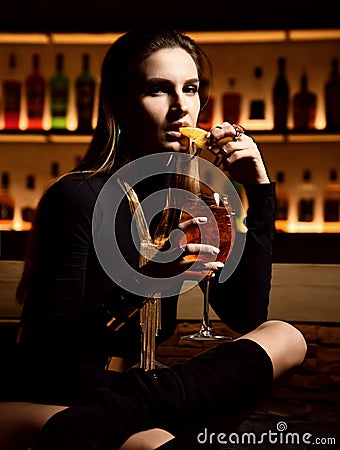 Beautiful fashion brunette woman in bar restaurant relaxing drinking orange aperol sprit cocktail Stock Photo