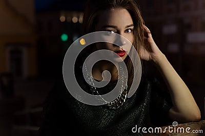 Beautiful girl with big lips with red lipstick on a city street at night near the lantern Stock Photo