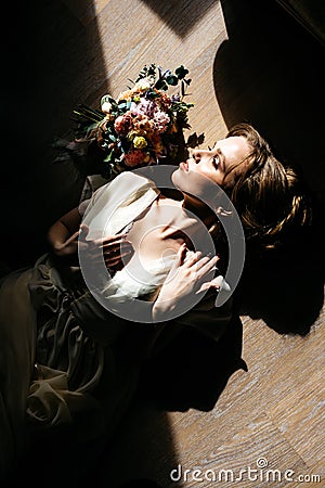 A beautiful girl, the bride, dressed in a negligee, lies on the floor Stock Photo