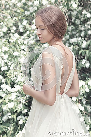 Beautiful girl bride in a light dress with delicate make-up and hair in the flower garden jasmine. Styled photo fane art Stock Photo