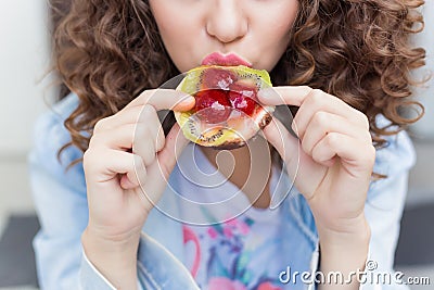 Beautiful girl with dark curly hair, eating a bright juicy fruit cake with a big appetite Stock Photo