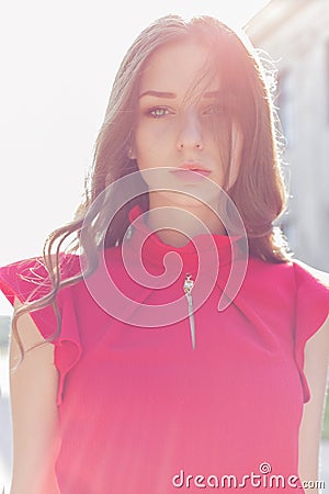 Beautiful girl in a red dress with a gentle look into the sun at sunset in bright sunny day Stock Photo