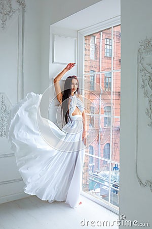 Beautiful girl in white dress by the window. romantic image. fashion indoor portrait of elegant woman in luxurious dres Stock Photo
