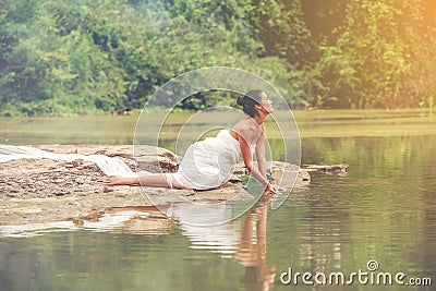 Beautiful sexy women in white light dress sitting on the rock. Sexy model sitting along the lake quiet and peace place for Stock Photo