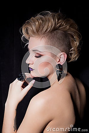 Beautiful young woman with blond hair with a short haircut with bright makeup and fashion bizhuterieyker earrings and ring, f Stock Photo
