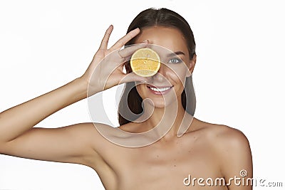 Beautiful young woman with perfect healthy skin and long brown hair day makeup bare shoulders holding orange lemon grapefruit Stock Photo