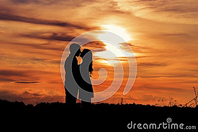 Beautiful shade loving happy couple kissing at sunset in a field of warm summer day Stock Photo