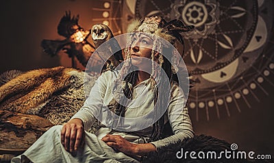 beautiful shamanic woman with owl in the interiors. Stock Photo