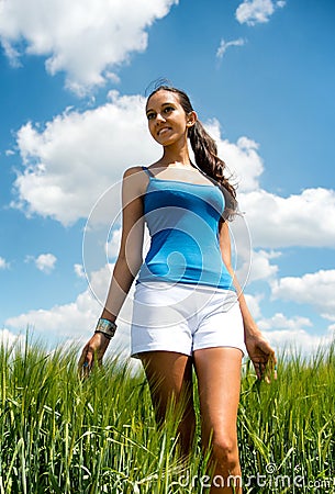 beautiful shapely young woman grassy field low angle view tanned shorts standing long green grass looking to side 41919993