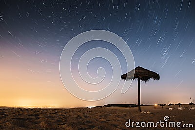 Beautiful shot of a beach at an evening with circular star trail in the sky Stock Photo