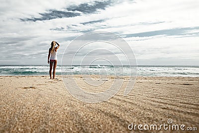 Beautiful shot of a blonde female standing on the seashore fixing her hair Editorial Stock Photo