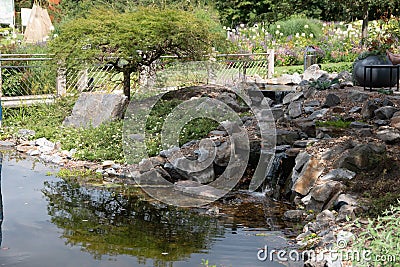 Beautiful shot of a man-made small waterfall over a rocky pond in the park Stock Photo