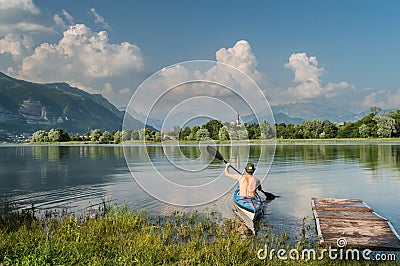 Beautiful shot of a person rowing a boat on the lake surrounded by trees and mountains Editorial Stock Photo
