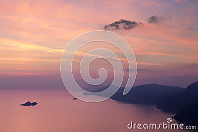 Beautiful shot of the sea surrounded by cliffs during the pink sunset Stock Photo