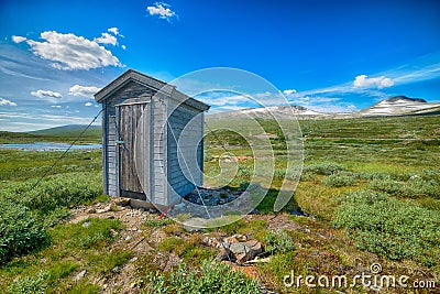 Beautiful shot of a wooden portable bathroom in the center of a green field Stock Photo