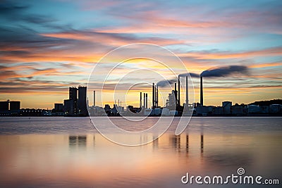 Beautiful silhouette of an industrial factory across the water at sunset in Aalbor, Denmark Editorial Stock Photo