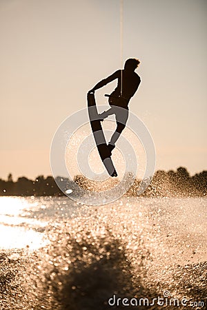 beautiful silhouette of wakeboarder athlete man jumping high making tricks in the air Stock Photo