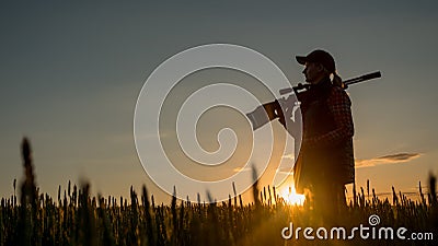 Silhouette of woman hunter. It stands in a picturesque place with a gun at sunset. Sports shooting and hunting concept Stock Photo