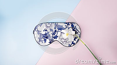Beautiful silk sleep mask for eyes with flowers pattern and white narcissus or daffodil flower on a pink blue background, panorama Stock Photo