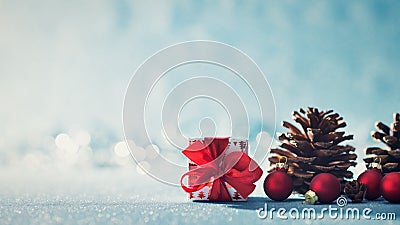 Beautiful simple Christmas background with copy space. Cute Christmas present, red ornaments and pine cones on blue background. Stock Photo