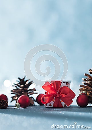 Beautiful simple Christmas background with copy space. Cute Christmas present, red ornaments and pine cones on blue background. Stock Photo