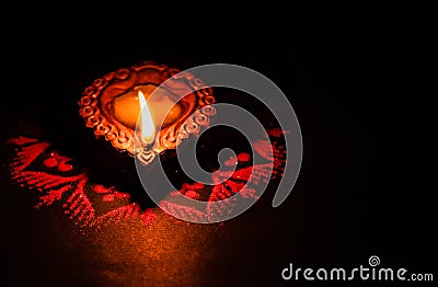 Beautiful single terracotta lamp glowing in the dark on a rangoli design with copy space Stock Photo