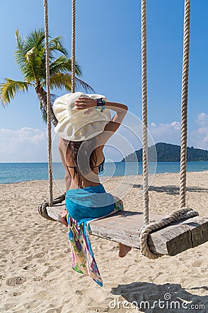 Beautiful, slender girl in bikie swinging on a swing Stock Photo