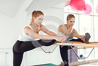 Beautiful slender woman in sportswear stretching near the ballet barre. Stock Photo