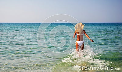 Beautiful slender young woman running in the sea waves Stock Photo