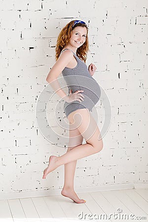 Beautiful slim pregnant woman posing by a white brick wall Stock Photo