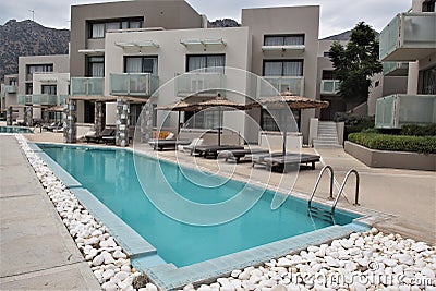 Beautiful small luxury hotel swimming pools with umbrellas and deck chairs in front of each apartments Stock Photo