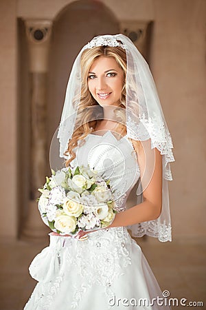 Beautiful smiling bride girl with bouquet of roses in wedding dr Stock Photo