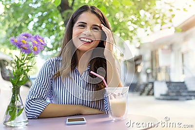 Beautiful smiling girl drinking coffee in the cafe outdoors Stock Photo